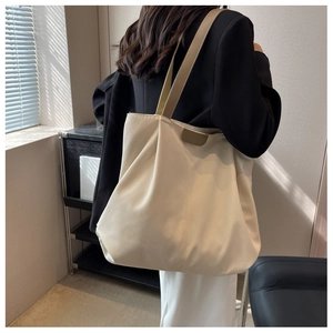 Close-up of beige canvas tote bag with khaki strap worn by a model in casual setting