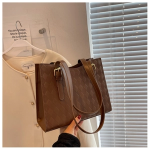 Detail showing the brown tote bag with quilted diamond pattern and golden metal buckle