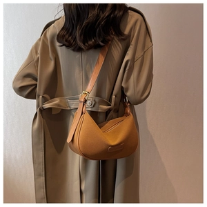 Detail of adjustable leather strap and caramel suede texture on crescent shoulder bag