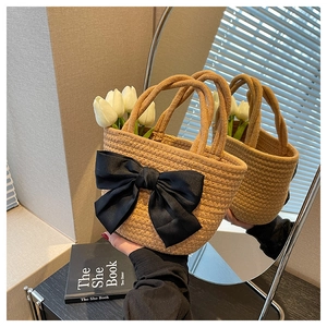Dettaglio borsa in paglia intrecciata con grande fiocco di raso nero e decoro tulipano