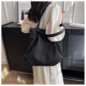 Matte black large capacity canvas tote bag worn over the shoulder for commute