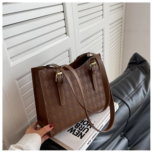 Detail of brown quilted tote bag with adjustable straps and golden metal buckles