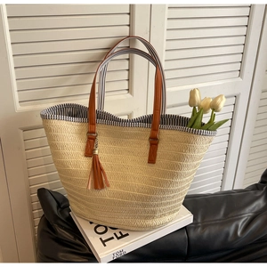 Detail of straw tote bag showing brown leather handles and striped inner lining