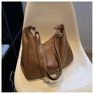 Detail of adjustable wide shoulder strap and gold buckle on caramel brown hobo bag