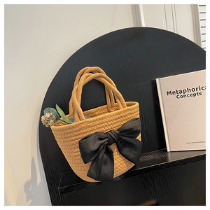 Dettaglio borsa a secchiello intrecciata gialla con fiocco in raso nero e fiori secchi