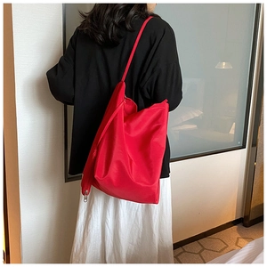 Vista dettagliata della grande borsa tote in tessuto oxford rosso indossata da una modella