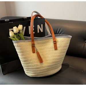 Detail of woven straw tote bag with brown leather handles and striped inner lining
