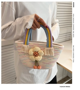 Détail du sac cabas tissé avec motifs de vagues colorés et pendentif floral en relief