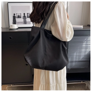 Detail of the embossed brand logo on the edge of a large black canvas tote bag
