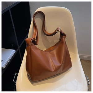 Detailed shot of caramel faux leather hobo bag with adjustable strap on white chair