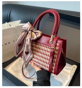 Detailed view of red houndstooth crossbody bag with woven handle and silk scarf detail
