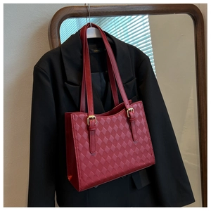 Detailed view of dark red quilted tote bag with gold hardware on a black blazer