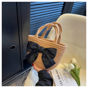 Dettaglio di una borsa a secchiello intrecciata kaki con un fiocco decorativo in raso nero