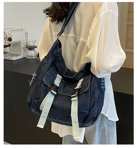Detail of blue denim messenger bag featuring double pockets with light blue straps and buckles