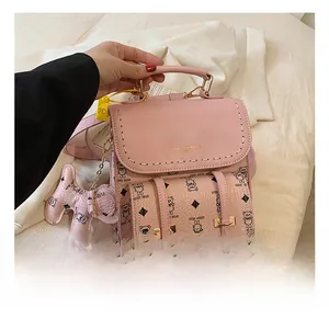 Vue détaillée du mini sac à dos rose avec motif ours, poignée dorée et breloque chien