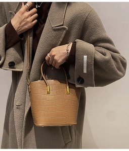 Detail of light brown croc-embossed bucket bag with gold hardware and top handle
