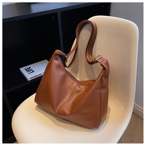 Close-up of caramel leather tote bag with vertical stitching and gold buckle details