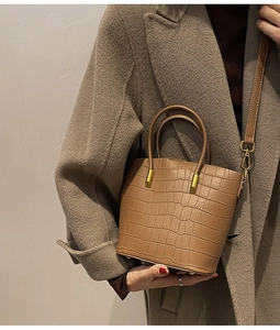 Close-up of brown crocodile pattern handbag with gold hardware and leather strap