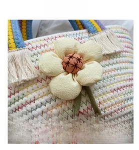 Dettaglio macro borsa intrecciata con cuciture colorate e decoro floreale in tessuto 3D