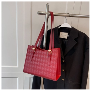Detail showing the red quilted tote bag with gold buckle on an adjustable strap