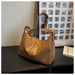 Detail of vintage brown leather hobo bag with vertical stitching and gold hardware accents