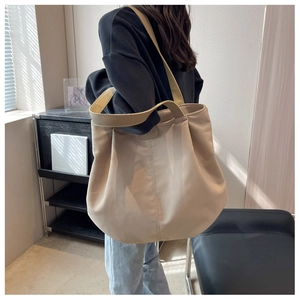 Detail of spacious khaki canvas tote bag with wide shoulder strap and leather patch