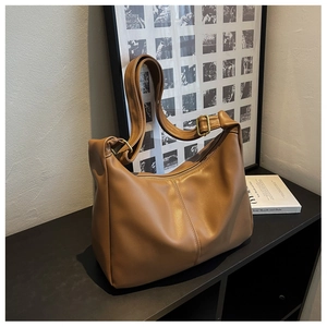 Detail of caramel brown faux leather hobo bag with adjustable strap and gold metal buckles