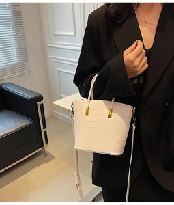 Detailed view of white crocodile embossed texture and gold metallic hardware on a bucket bag