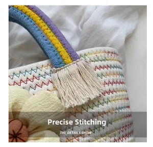 Dettaglio delle cuciture precise sulla borsa in paglia bianca con manici arcobaleno e fiore