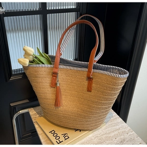 Detail of hand-woven straw tote with leather straps and blue striped fabric lining