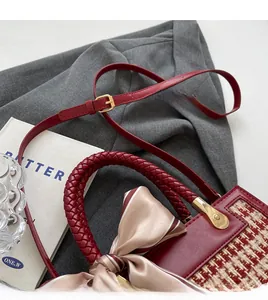 Close-up of red woven handle and red-white plaid handbag with striped silk scarf detail