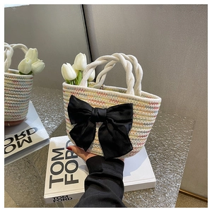 Dettaglio della borsa a mano intrecciata con motivi colorati e fiocco nero decorativo