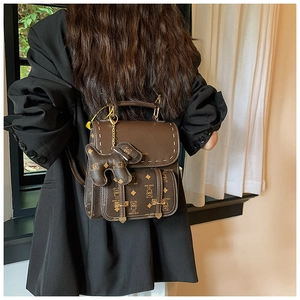 Détail d'un sac à dos vintage marron avec motif d'ours et pendentif en cuir sur le côté