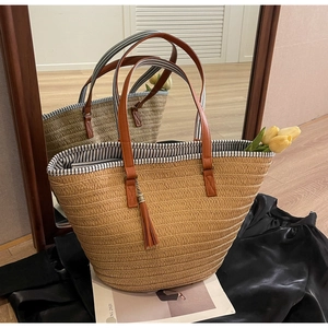 Detail of straw woven tote bag with brown leather handles and striped inner lining