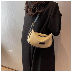Close-up of beige crescent bag with black strap and gold buckle on a black coat