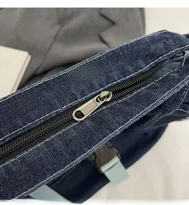 Detailed close-up of smooth metal zipper and white contrast stitching on denim tote bag
