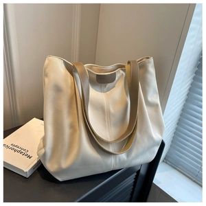 Close-up of cream canvas tote bag featuring dual straps and embossed BUDBAG leather logo