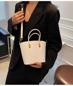 Close-up of white crocodile pattern bucket bag with gold hardware and strap details