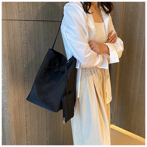 Dettaglio della borsa tote in nylon nero con etichetta laterale e astuccio coordinato