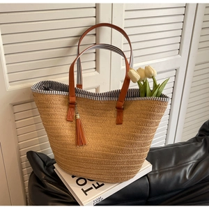 Detail of straw woven tote with leather handles and blue striped lining for beach vacation