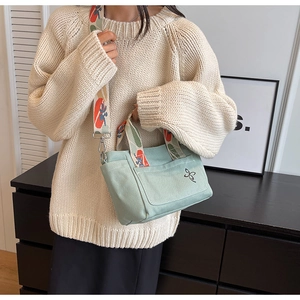 Mint green canvas tote bag featuring geometric patterned wide strap and floral embroidery
