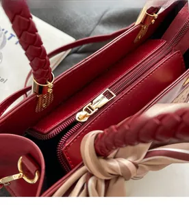 Detailed close-up of smooth gold metal zipper and woven handle on red crossbody bag