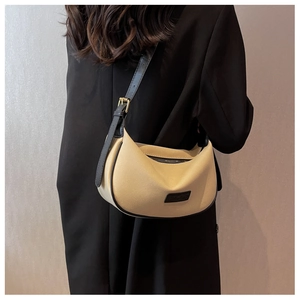Detail of the minimalist beige half-moon bag with black leather trim and metal buckle