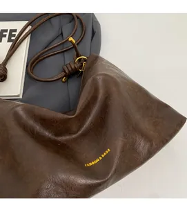 Detail of soft dark brown leather tote bag showing smooth texture and drawstring handle