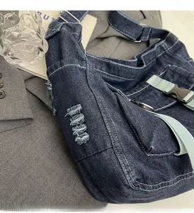 Detail of dark blue denim tote with white stitching and light green nylon strap