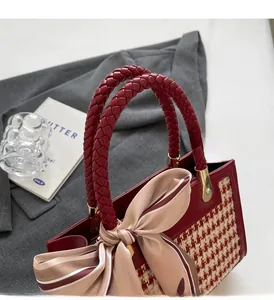 Detail view of woven red handle and houndstooth texture with silk scarf bow