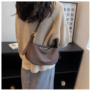 Rear view of brown nylon crescent bag worn as a shoulder bag in minimalist setting