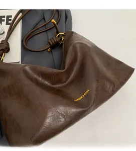 Detail of dark brown tote bag with vintage leather texture and decorative knotted strap