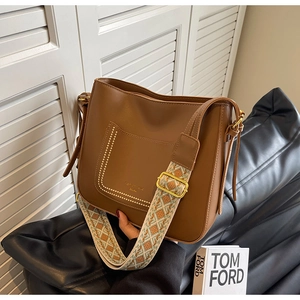 Close-up of brown bucket bag showing decorative stitching and ethnic jacquard strap