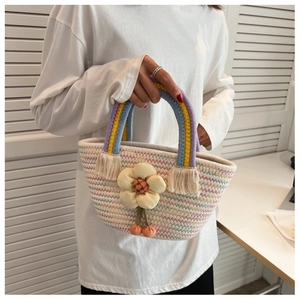 Détail d'un sac seau tissé avec des anses arc-en-ciel, pompons et fleur jaune en 3D